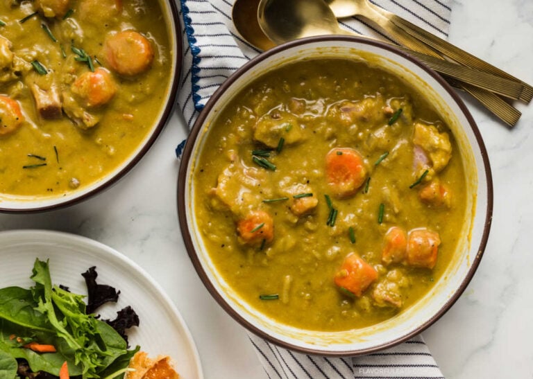 Two bowls of Slow Cooker Split Pea Soup with utensils and salad beside them.