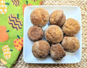 Cinnamon Pumpkin Mini Muffins on a square white plate with a pumpkin napkin beside it.