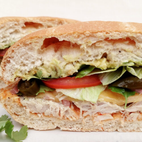 Turkey & Avocado Torta with Chipotle Aioli shown cut in half to see the inside.