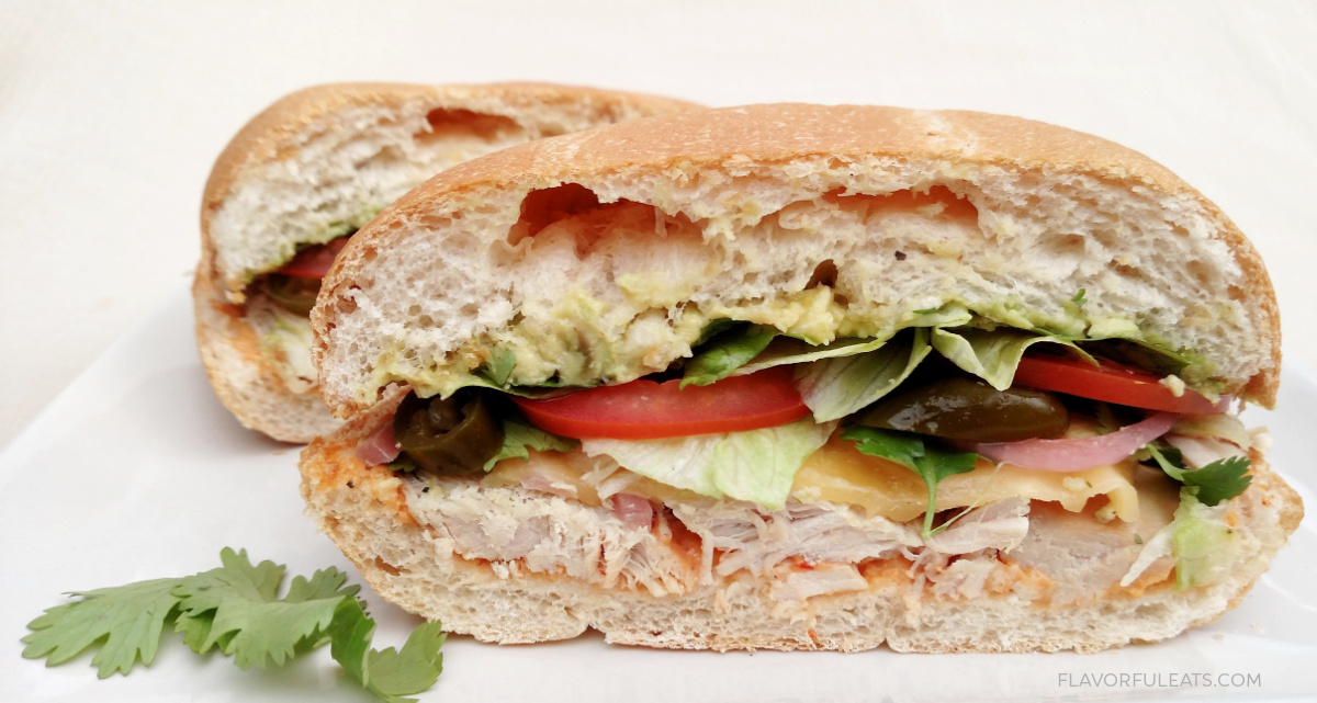 Turkey & Avocado Torta with Chipotle Aioli shown cut in half to see the inside.