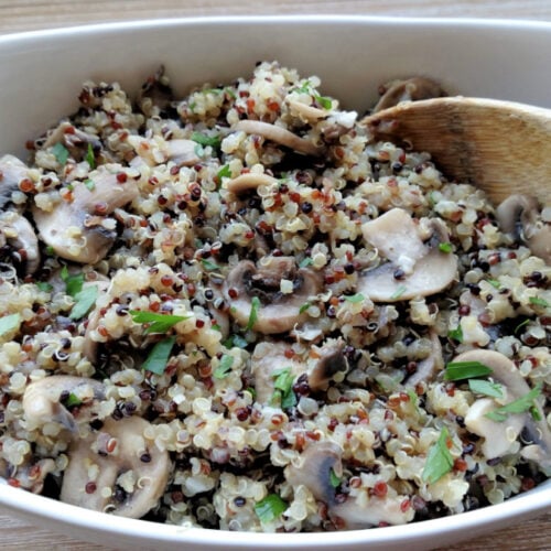 Mushroom Garlic Quinoa in a serving bowl with a wooden spoon.