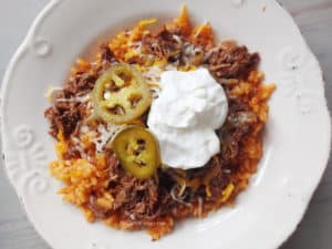 Burrito bowl made with Mexican rice, leftover barbacoa, sour cream, and pickled jalapenos.