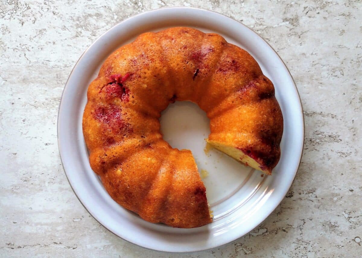 Lemon Raspberry Bundt Cake on a white plate with a slice removed.