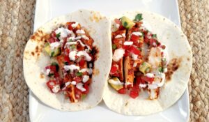 Two Achiote Chicken Tacos with Creamy Chipotle Sauce on a plate.