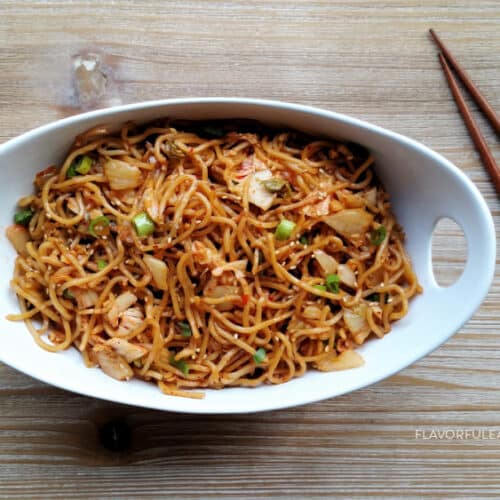 Spicy Kimchi Garlic Noodles in a white bowl with chopsticks beside it