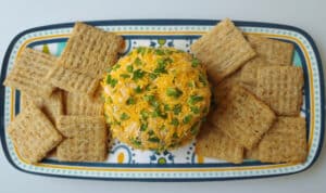 Cheddar Jalapeno Taco Cheese Ball on a platter with crackers.