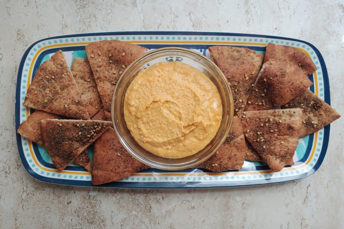 Toasted Za'atar Pita Chips on a platter with a bowl of hummus.