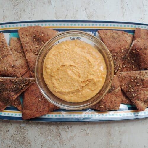 Toasted Za'atar Pita Chips on a platter with a bowl of hummus.