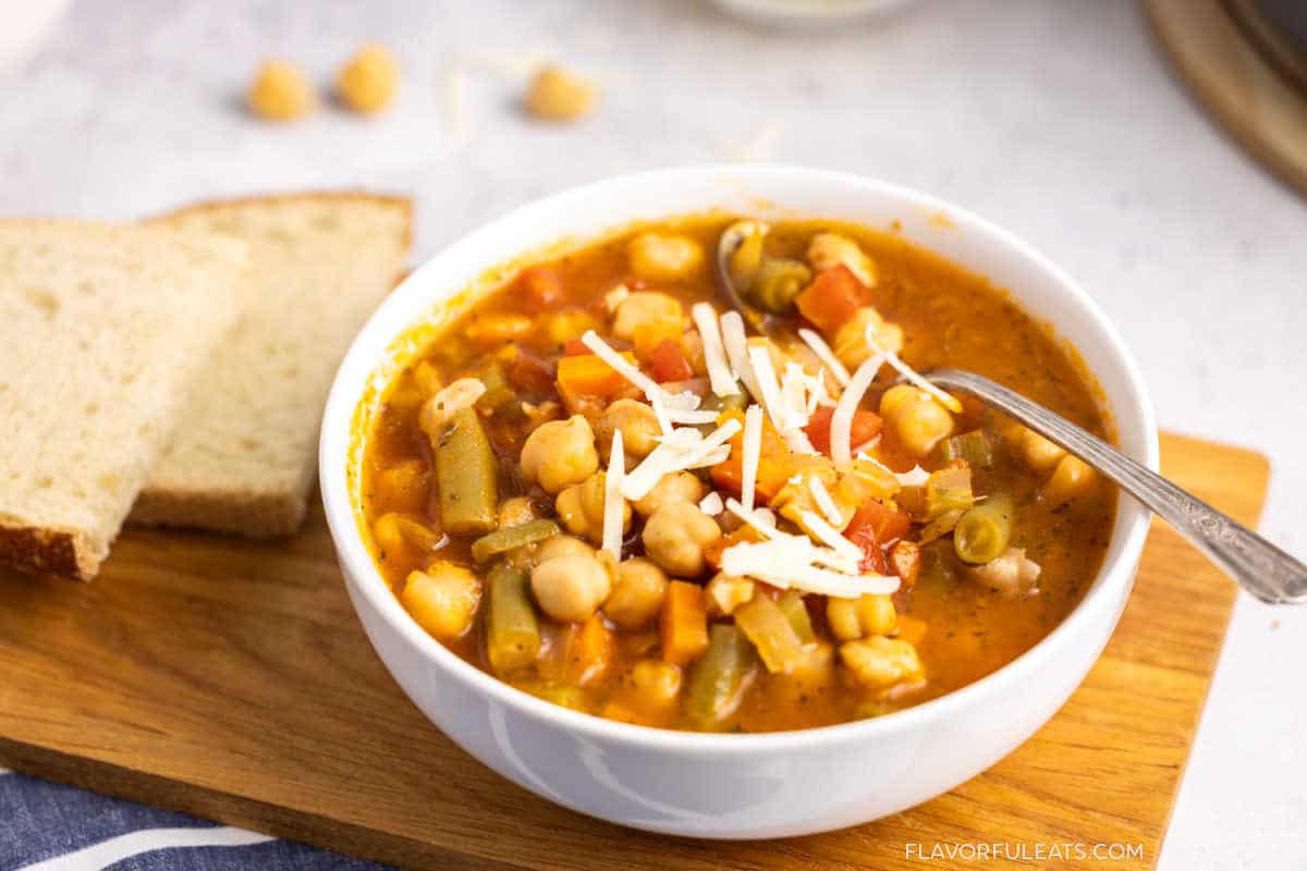 A close-up bowl of Italian Chickpea Vegetable Soup with bread beside it.