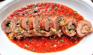 Slow Cooker Beef Braciole fanned out on a white platter for serving.