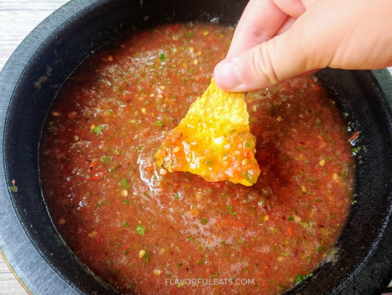 A tortilla chip dipping in Roasted Tomato Habanero Salsa.