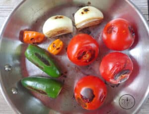 Charred, roasted vegetables in a pan for Roasted Tomato Habanero Salsa.