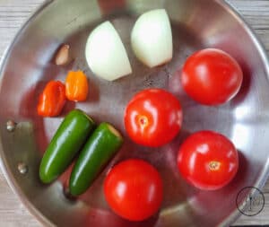 Vegetables roasting in a pan for Roasted Tomato Habanero Salsa.