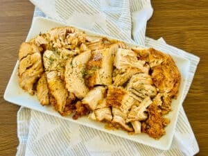 Slow Cooker Cajun Butter Turkey Breast carved on a white platter.