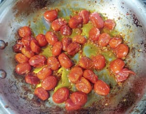 Grape tomatoes in a pan with garlic after they're cooked