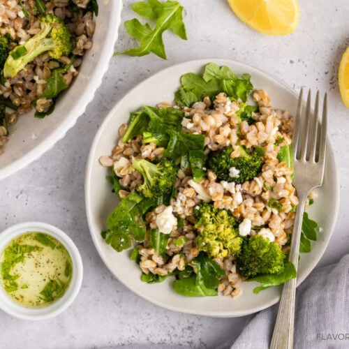 Roasted Broccoli Farro Salad on a plate with a fork and the serving bowl beside it.