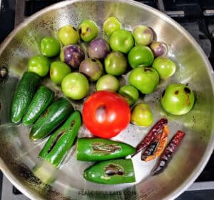 The peppers, tomato, and tomatillos cooking in a pan for Chile de Arbol Tomatillo Salsa.