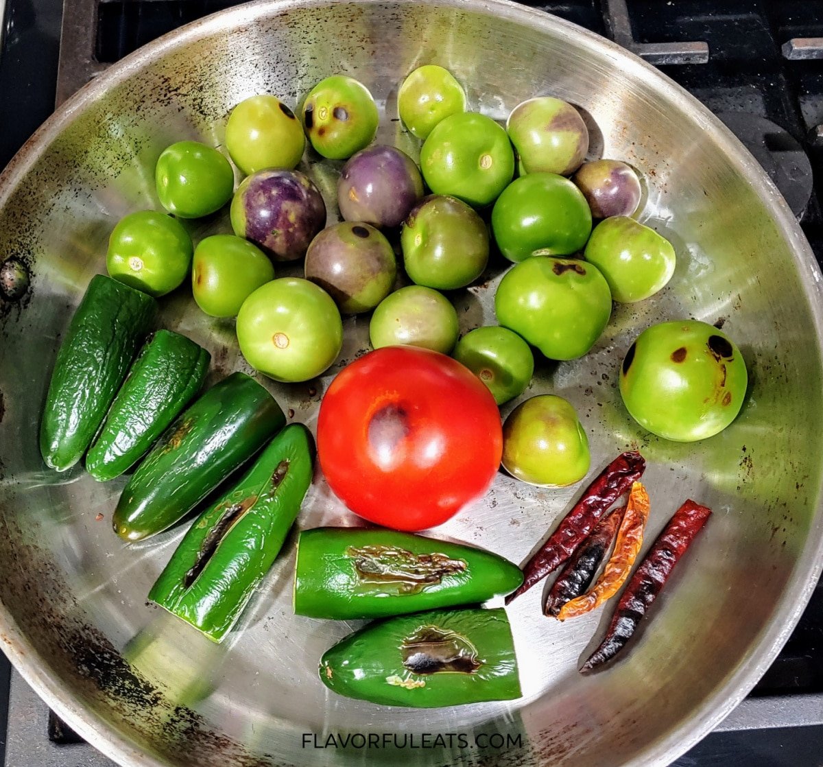 The peppers, tomato, and tomatillos cooking in a pan for Chile de Arbol Tomatillo Salsa.