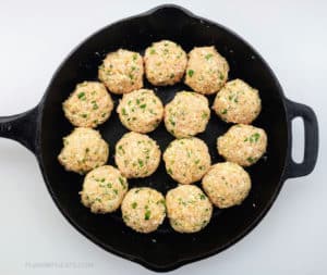 Uncooked meatballs in pan