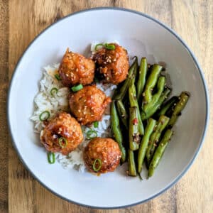 Slow Cooker Spicy Korean Meatballs over rice in a white bowl.