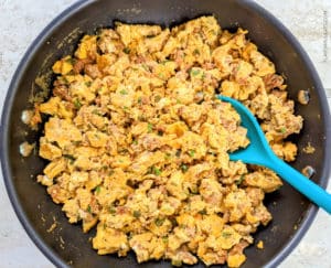 A skillet with cooked scrambled eggs & chorizo.
