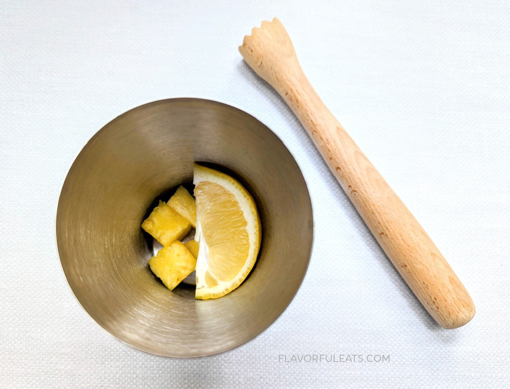 A cocktail shaker wit lemon and pineapple in it.