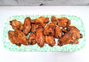 A pretty serving plate with sauced Slow Cooker Chicken Wings stacked on it.
