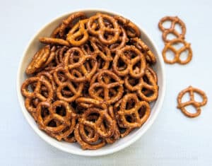 Spicy Seasoned Pretzels in a big, white bowl with a couple pretzels beside it.