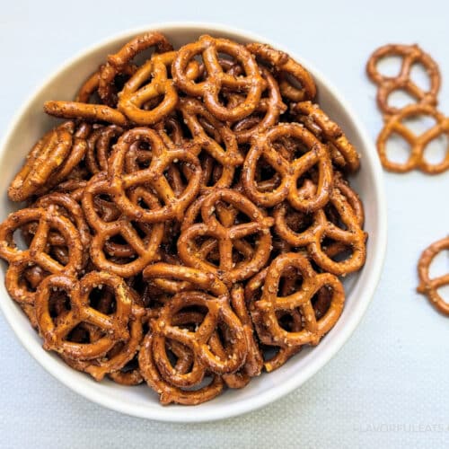 Spicy Seasoned Pretzels in a big, white bowl with a couple pretzels beside it.