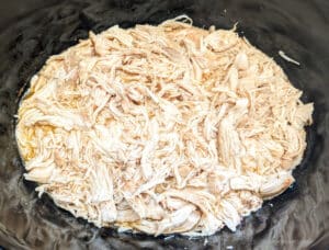 Cooked and shredded chicken in a slow cooker ready for Slow Cooker Chicken Sandwiches with Alabama White Sauce
