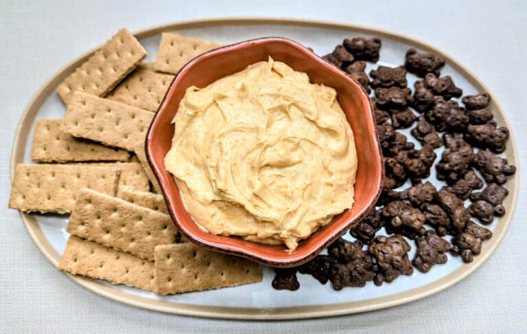 Pumpkin Cheesecake Dip in a bowl with Graham crackers and chocolate Teddy Grahams beside it on a tray