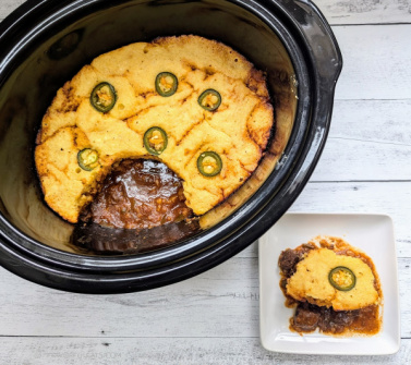 Slow Cooker BBQ Beef Cornbread Casserole shown both in the slow cooker and beside that, served on a plate