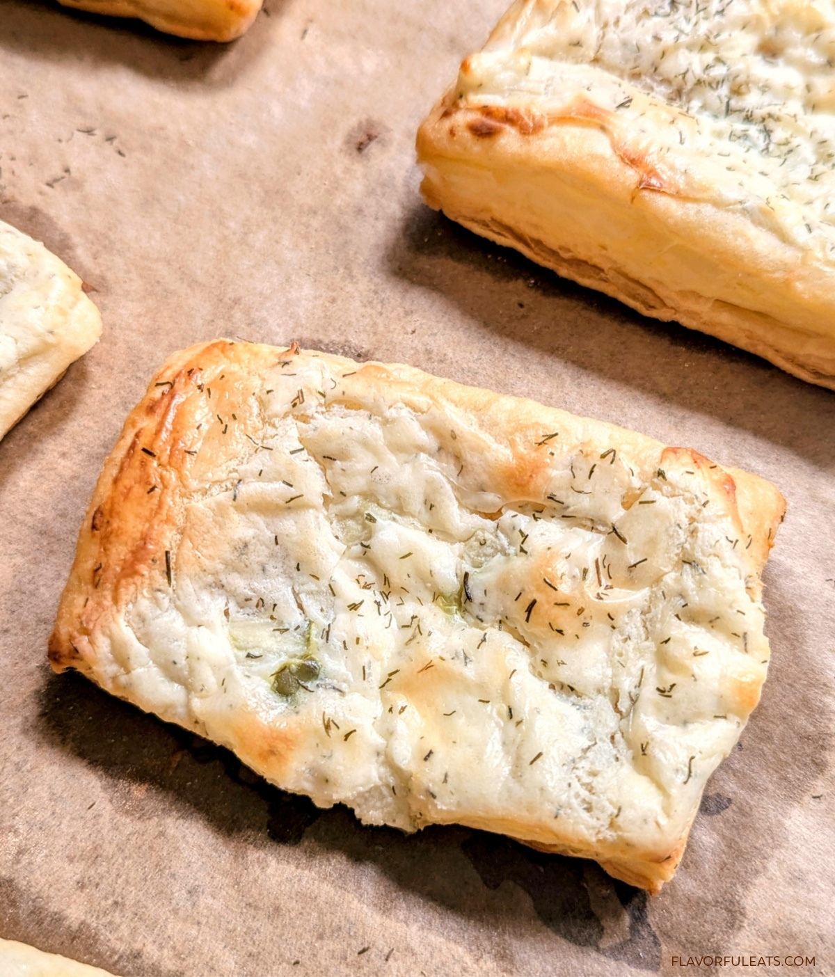 A close up of a Dill Pickle Puff Pastry Appetizers on a baking sheet after being baked.