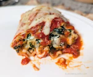 Cheesy Spinach Lasagna Roll Up on a white plate showing all the delicious, cheesy goodness inside.