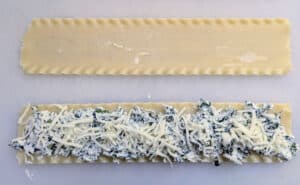 A lasagna noodle with the spinach/cheese mixture spread on it before it's rolled up for Cheesy Spinach Lasagna Roll Ups