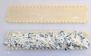 A lasagna noodle with the spinach/cheese mixture spread on it before it's rolled up for Cheesy Spinach Lasagna Roll Ups