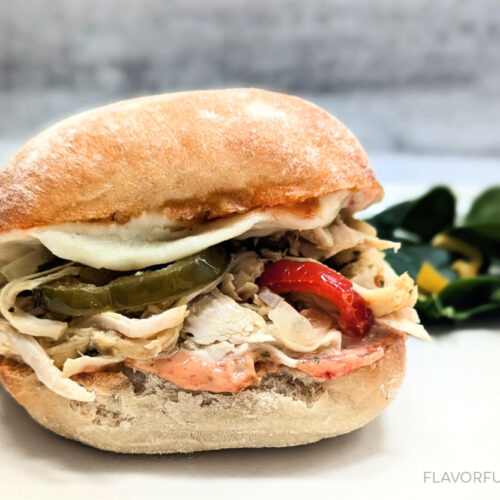 Slow Cooker Spicy Italian Chicken Sandwich on a plate with salad beside it.