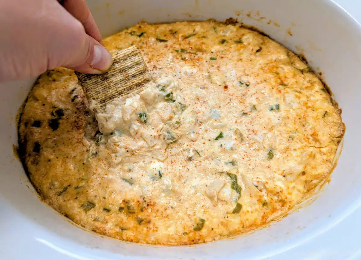 Slow Cooker Creole Crab Dip with a cracker dipping into it.
