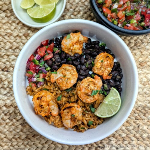 Achiote Shrimp Skewers in a burrito bowl with Mexican rice, black beans, and pico de gallo.