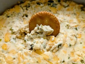 Slow Cooker Jalapeno Pickle Dip with a cracker dipping in it.
