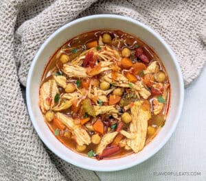 Slow Cooker Harissa Chicken Soup in a bowl with cilantro garnished on top.