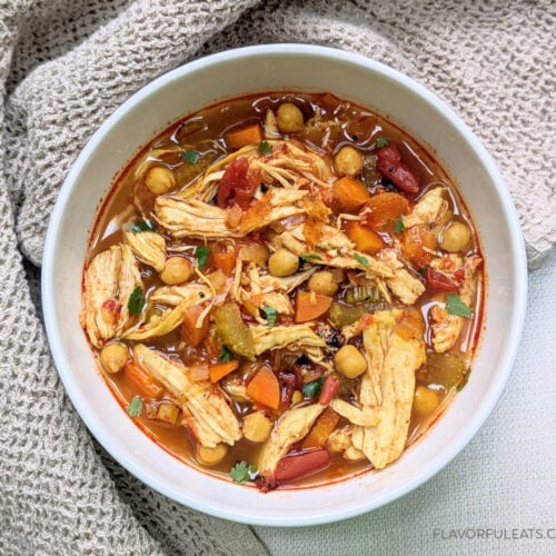 Slow Cooker Harissa Chicken Soup in a bowl with cilantro garnished on top.