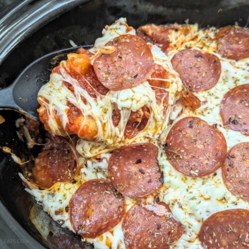 Slow Cooker Sausage & Gnocchi Pizza Casserole with a spoon pulling a cheesy serving out of the slow cooker.
