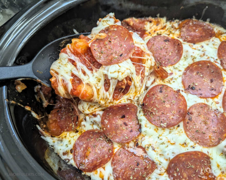 Slow Cooker Sausage & Gnocchi Pizza Casserole with a spoon pulling a cheesy serving out of the slow cooker.