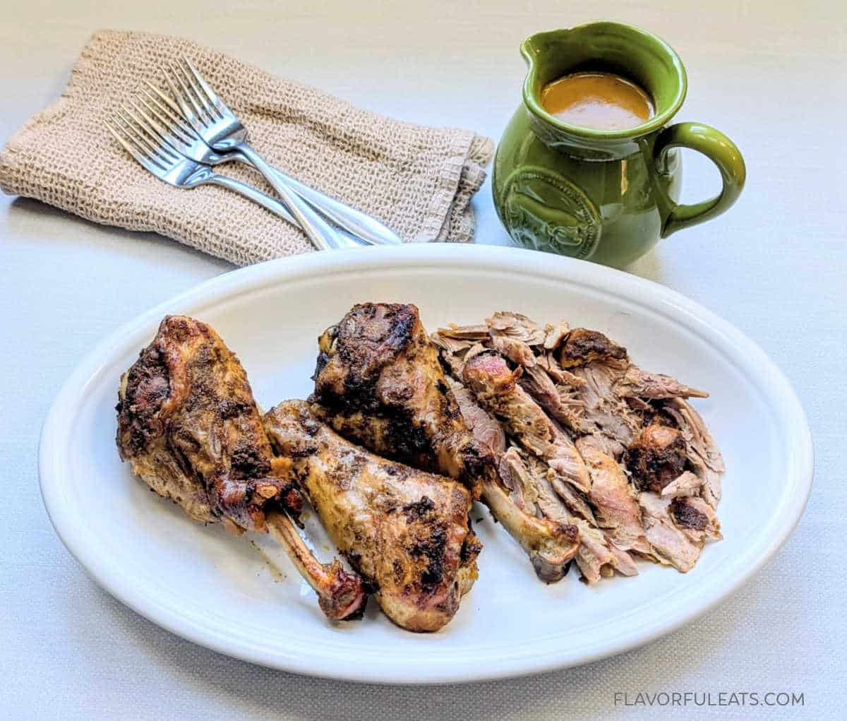 Slow Cooker Turkey Legs with Onion Gravy on a platter with the gravy boat beside it.