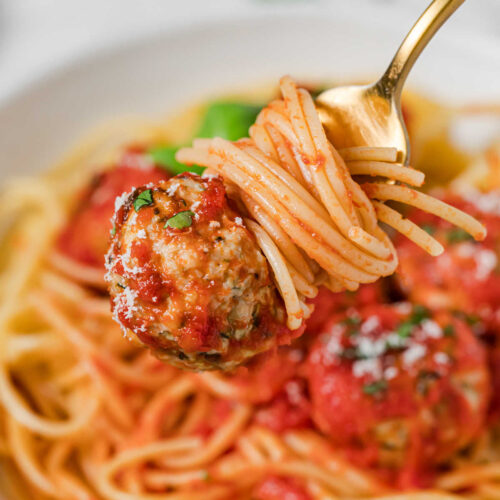 Baked Turkey, Zucchini & Feta Meatballs on a fork with spaghetti.