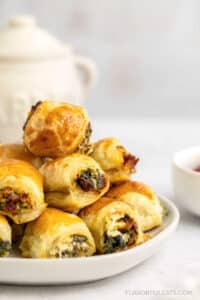 Sun-Dried Tomato & Spinach Puff Pastry Bites stacked on a serving plate.