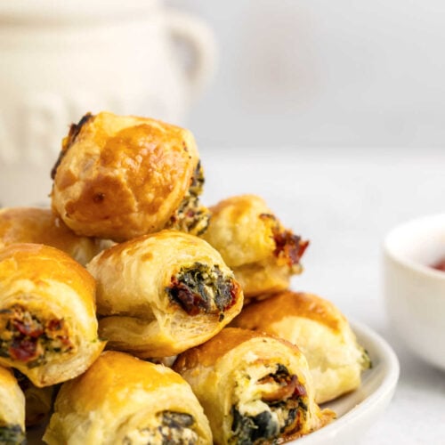 Sun-Dried Tomato & Spinach Puff Pastry Bites stacked on a serving plate.
