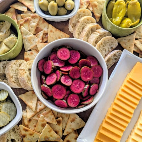Pink Pickled Cucumbers up close on a charcuterie platter.