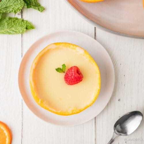 Orange Lemon Posset on a small white plate with a raspberry garnished on top.